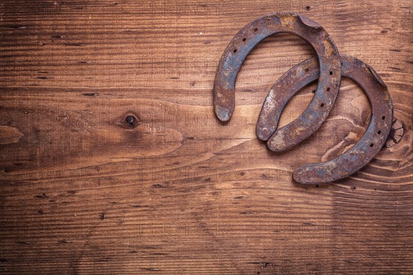Copyspace image two old cast iron metal western horse shoeing accessories horseshoes on antique wooden background happy concept