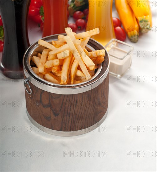 Fresh french fries on a wood bucket with selection of beers and fresh vegetables on background