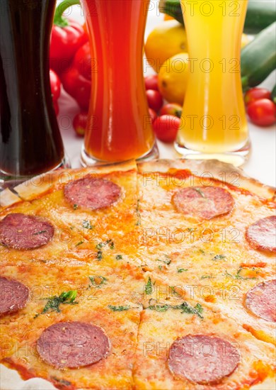 Italian original thin crust pepperoni pizza with selection of beers and vegetables on background