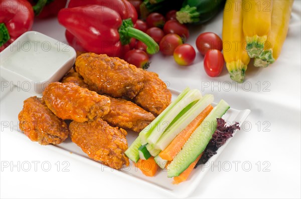 Classic buffalo chicken wings served with fresh pinzimonio and vegetables on background