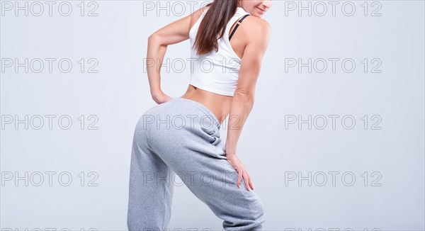 No name portrait. Young white fitness woman wearing sportswear standing over white wall background. Fitness concept. Mixed media