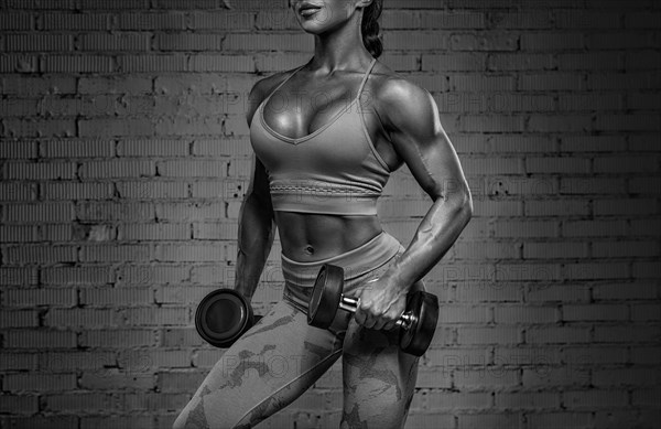 Black and white image of a sexy fitness woman. A beautiful sportswoman is training in the gym. Mixed media