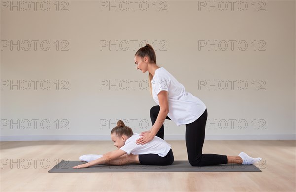 Beautiful female teacher helps a little girl stretch in a gymnastics class. The concept of education