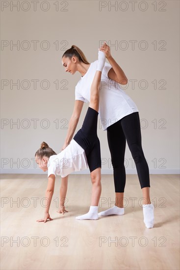 Beautiful woman teacher and a little girl perform dance movements in a bright studio. The concept of education