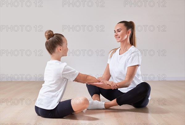 Beautiful female teacher and a little girl are holding hands in a gymnastics class. Concept of education