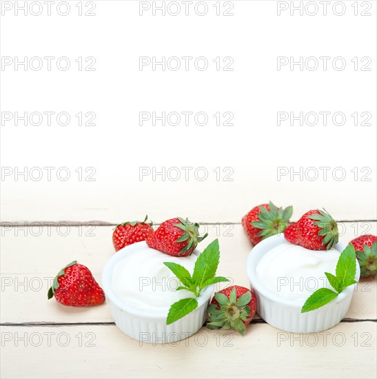 Organic Greek yogurt and strawberry over white rustic wood table