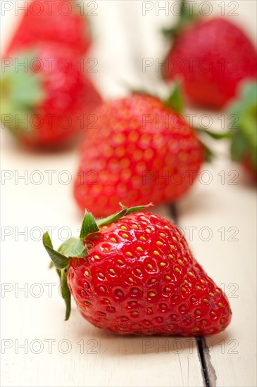 Fresh organic strawberry over white rustic wood table