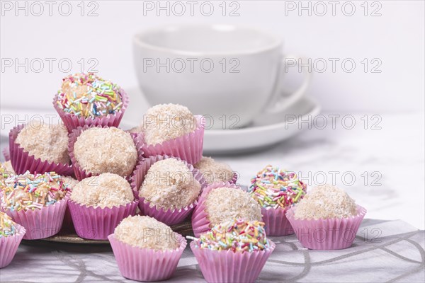 Light rum balls in pink paper cups with colourful sprinkles and coconut