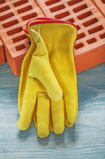 Building bricks yellow protective gloves on wooden board construction concept