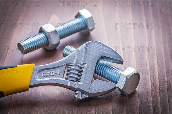 Adjustable spanner and bolt on vintage wooden board Construction concept