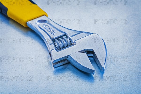 Adjustable metal spanner on a metallic background Design concept