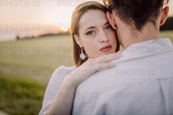 Couple in love in a field at sunset on a date in summer. Wedding engagement of a young couple