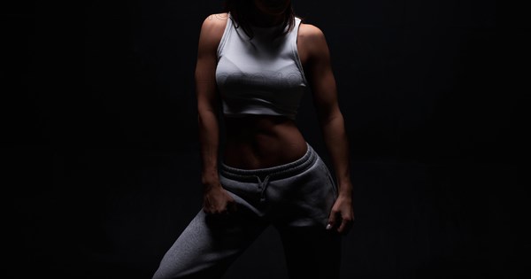 Athletic fitness woman posing in the studio on a dark background. Photo of an attractive woman in fashionable sportswear. Sports and healthy lifestyle. Mixed media