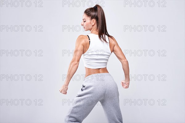 Young white fitness woman wearing sportswear standing over white wall background. Fitness concept. Mixed media