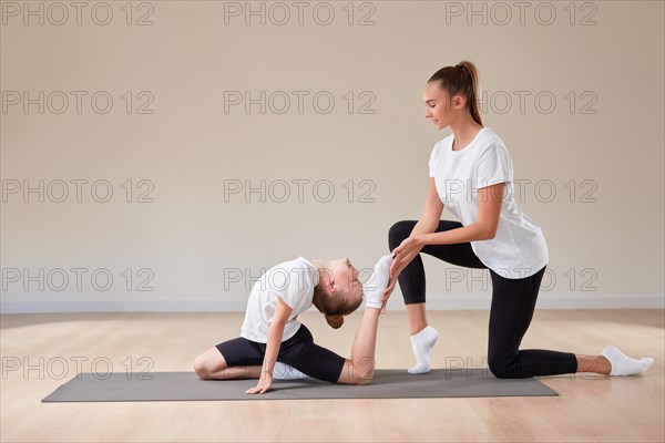 Beautiful female teacher helps a little girl stretch in a gymnastics class. The concept of education