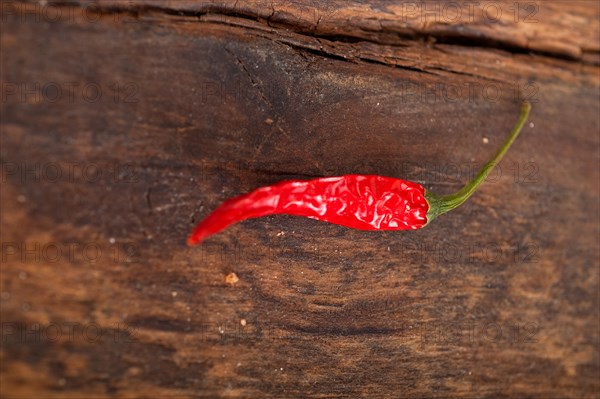 Dry red chili peppers over old wood table