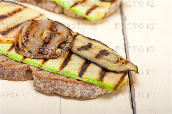 Grilled vegetables on rustic bread over wood table