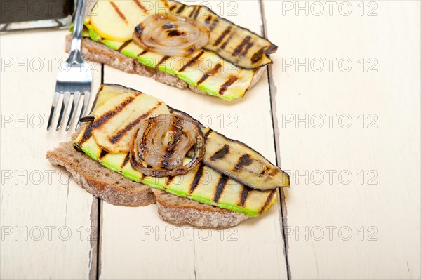 Grilled vegetables on rustic bread over wood table