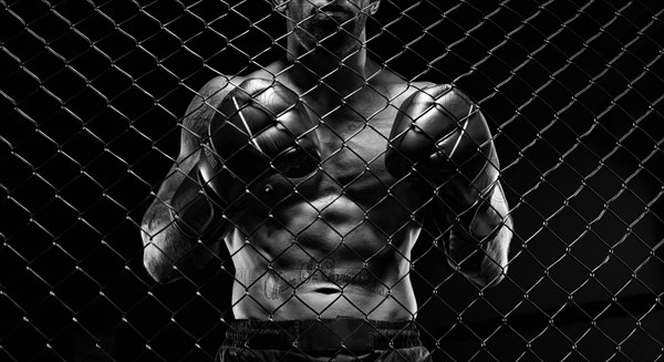 Black and white image of a man in a boxing cage. The concept of sports