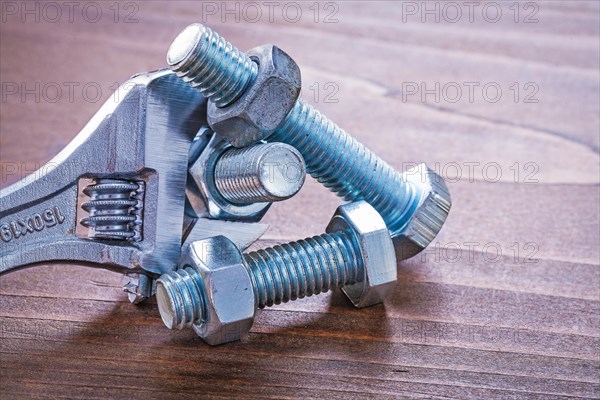 Adjustable spanner stainless threaded bolt details and screw nuts on vintage wooden board construction concept