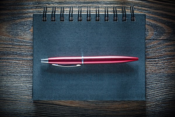 Black notebook pen on vintage wooden board top view