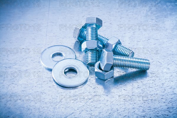 Metal threaded screws Nuts and bolts Washers on metallic background Construction concept