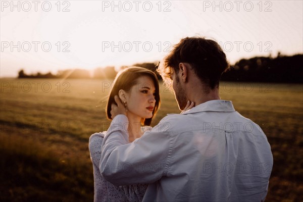 Couple in love in a field at sunset on a date in summer. Wedding engagement of a young couple