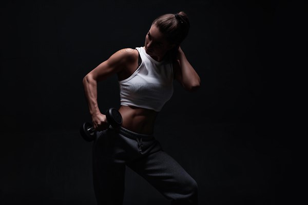 Athletic fitness woman posing in the studio on a dark background. Photo of an attractive woman in fashionable sportswear. Sports and healthy lifestyle. Mixed media