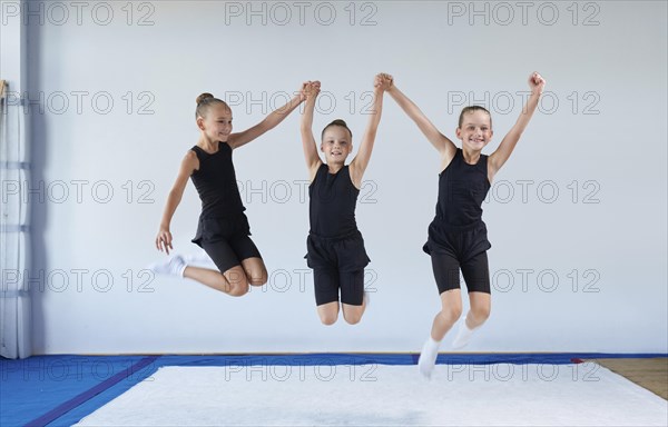 Group of cheerful children are jumping in the gym. Gymnastics concept. Mixed media
