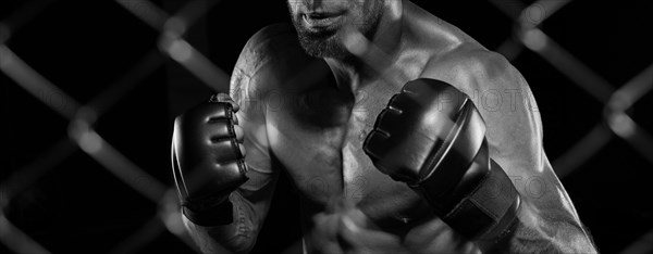 Black and white image of a man in a boxing cage. The concept of sports