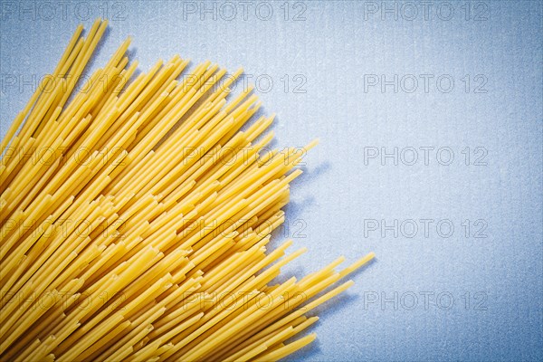 Yellow thin spaghetti on blue background food and drink concept