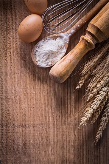 Organised copyspace eggs corolla spoon with flour rolling pin ears of wheat on wooden board food and drink still life