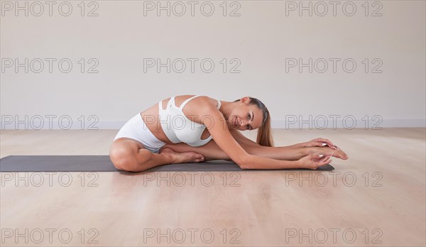 Flexible woman is training in a light studio. The concept of gymnastics