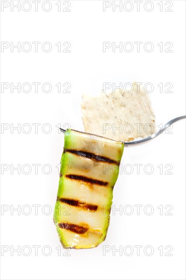 Grilled zucchini courgette on a fork with cracker macro close up