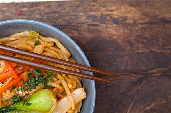 Hand pulled stretched Chinese ramen noodles on a bowl with chopstick