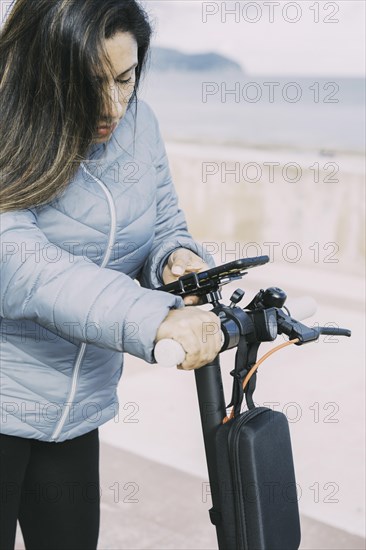 Side view of Beautiful latin woman riding her motorized scooter in the city