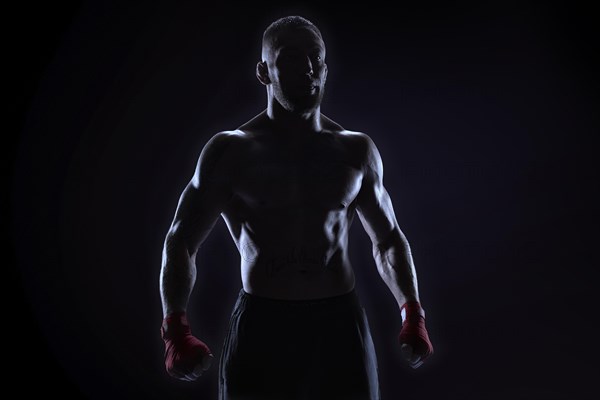 Kickboxer in red bandages posing on a blue background. The concept of mixed martial arts. MMA