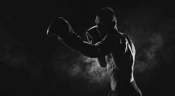 Kickboxer in black gloves posing on a background of smoke. The concept of mixed martial arts. MMA