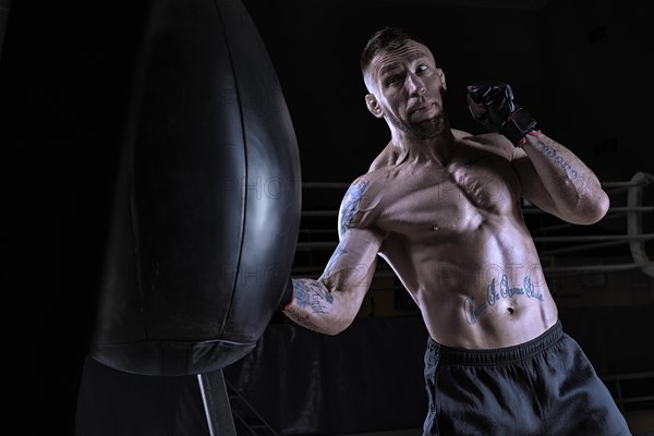 Kickboxer hits the bag. Sports training. The concept of mixed martial arts. MMA