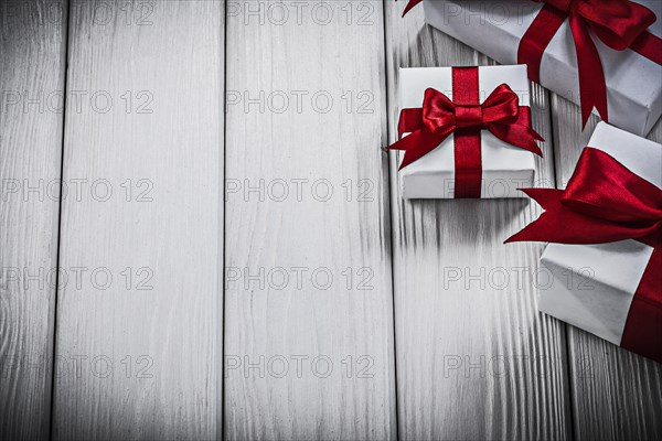 Gift boxes with red bows on wooden board holidays concept