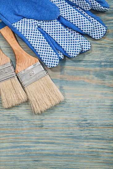 Composition of paintbrushes safety gloves on wooden board construction concept