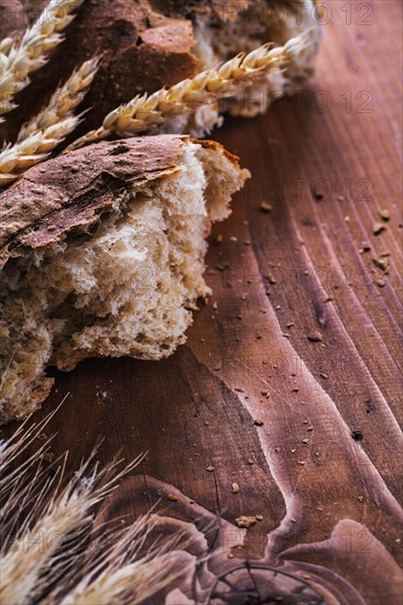 Slice of bread with ears of wheat on an old wooden board