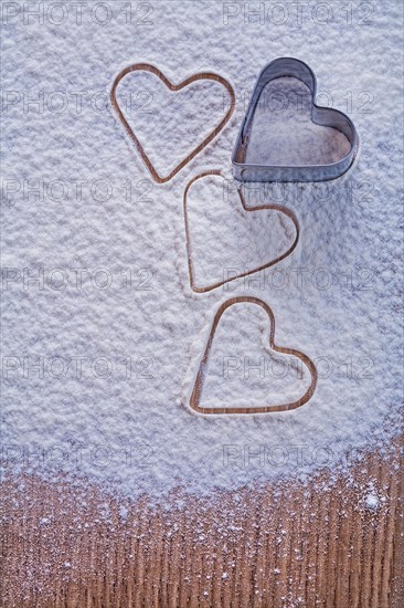 Cookie cutter in the shape of a heart on flour and wooden board Food and drink concept