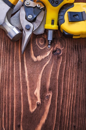 Measuring tape Protective glove Claw hammer Screwdriver and wire cutter on brown wooden board