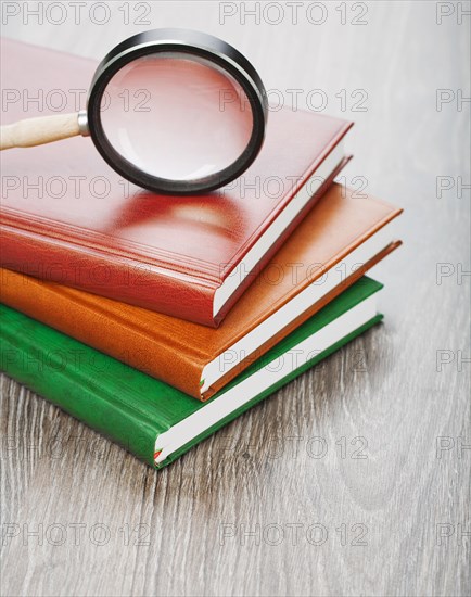 Notebooks and magnifying glass on a wooden background