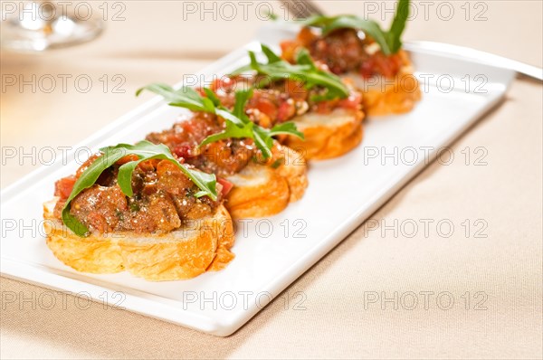 Fresh tipycal italian bruschetta with tomato and arugula on top