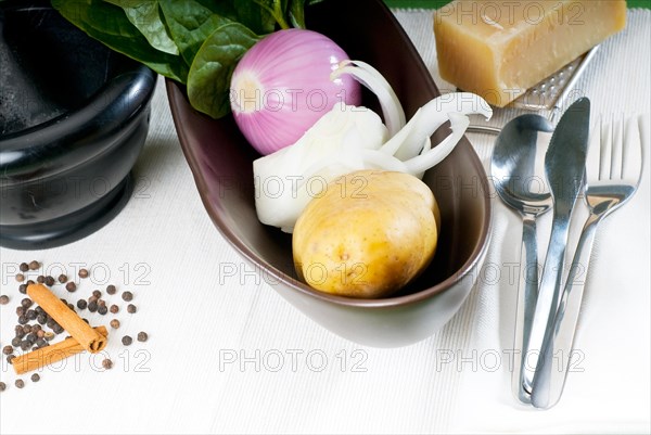 Bowl of fresh vegetable with spice and mortar beside