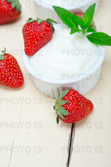 Organic Greek yogurt and strawberry over white rustic wood table