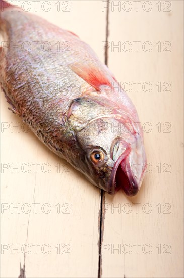 Fresh whole raw fish on a wooden table ready to cook