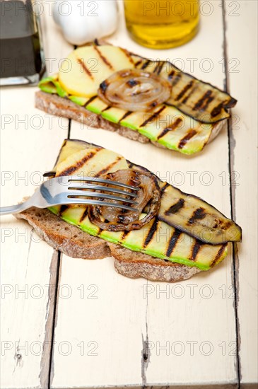 Grilled vegetables on rustic bread over wood table